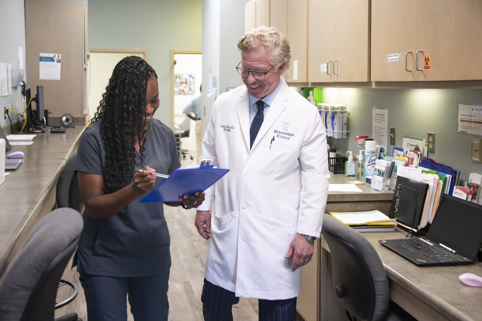 Nephrologist and staff member smiling while reviewing patient charts at Mississippi Kidney nephrology clinic.