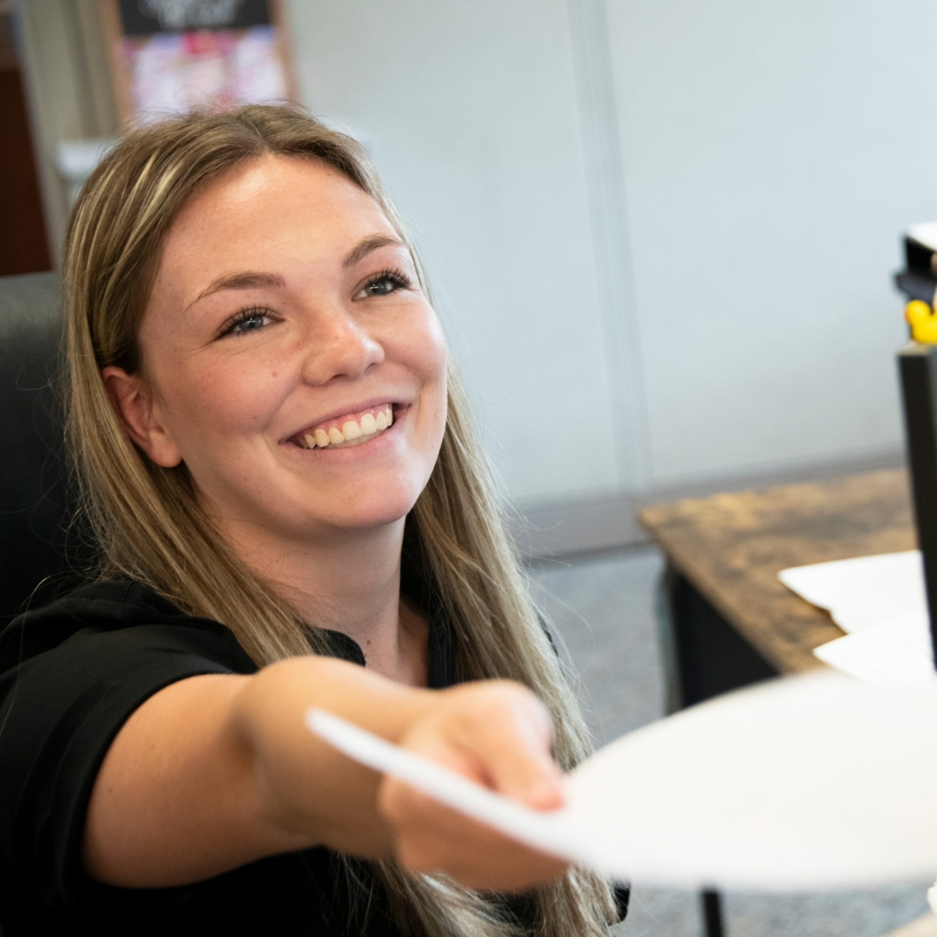Receptionist smiling while handing check-in documents to a patient at a Mississippi kidney nephrology office.